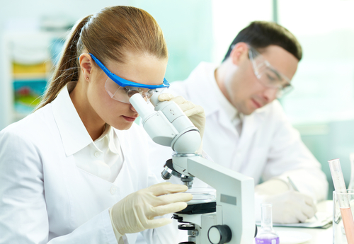 Two lab technicians looking through a microscope